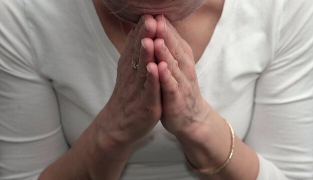 woman praying to god with hands together white grey background stock photo