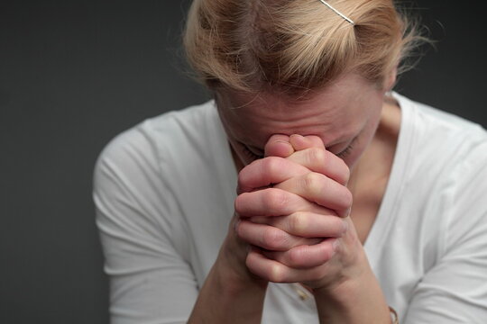 woman praying with hand over her face on grey background stock photo