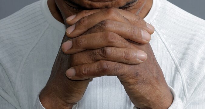 man praying to god with hands together stock photo