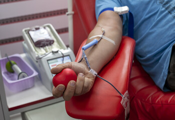 Close-up of donor holding ball in his hand and donating blood at the lab