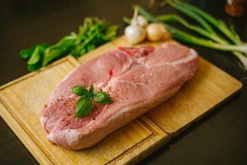 Chuletas de cerdo en tabla de madera con albahaca