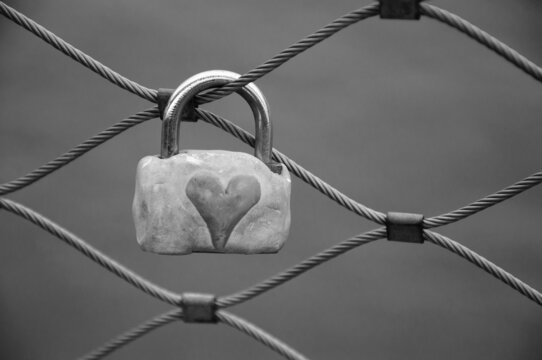Love lock with heart attached to bridge in Paris, France. Valentine's day background. Black white historic photo
