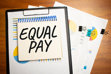 Equal Pay is written on a notepad on an office desk