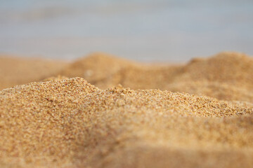Sand closeup with blurred sea on the background.