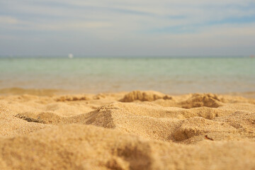 Fototapeta na wymiar Sand closeup with blurred sea on the background.