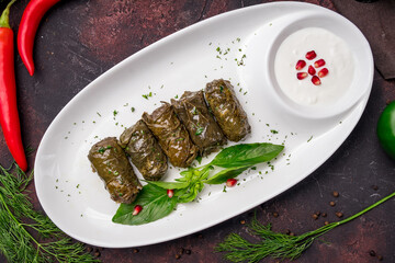 Dolma georgian kitchen with sour cream on white plate on dark table top view