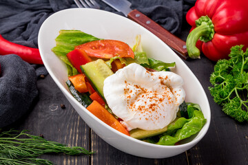 Vegetable salad with poached egg on white plate