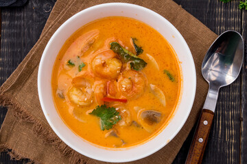 Tom Yam soup with shrimps on white bowl on dark table top view
