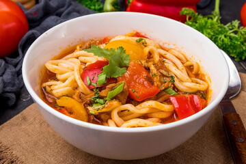 Lagman asian soup with meat, vegetables and noodles, dark table, uzbek cuisine