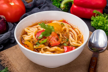 Lagman asian soup with meat, vegetables and noodles, dark table, uzbek cuisine