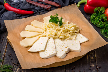 Suluguni cheese sliced on the board on dark table - 482469322