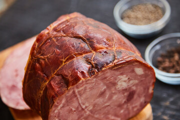 Homemade ham, sliced on a wooden table on a cutting board with spices and salt. Traditional ham homemade, ready to eat, delicious breakfast. The concept of meat products.
