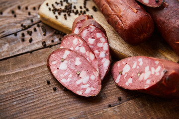 Homemade sausage with garlic cut into slices lies on a wooden table on a cutting board with spices and garlic. Traditional sausage, ready to eat, delicious breakfast. 