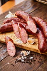 Homemade sausage with garlic cut into slices lies on a wooden table on a cutting board with spices and garlic. Traditional sausage, ready to eat, delicious breakfast. T