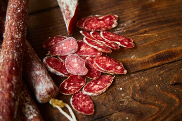 Factory for the production of meat products, boiled and smoked sausages. Traditional spicy sausage, ready to eat, lies sliced on a wooden table. The concept of handmade meat products. 