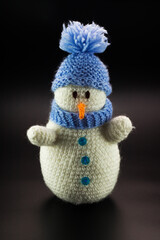 Toy snowman with a carrot, blue buttons and a blue knitted hat and scarf