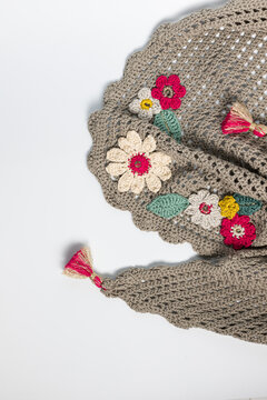 Crochet fun handmade shawl with floral ornaments over white background.
