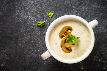 Mushroom Cream Soup on dark stone table. Hot Vegetarian dish, creamy soup. Plant based food.