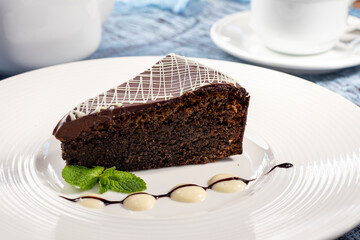 Poppy seed cake with creamy sauce and mint on white plate