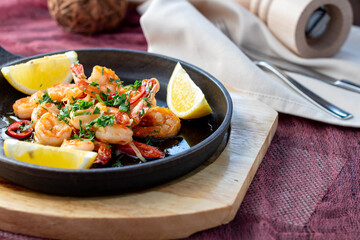Shrimp in sweet sour sauce with lemon on black iron pan