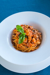 Delicious Italian pasta with seafood in tomato sauce in a white plate. Delicious dinner at the restaurant. A dish of Mediterranean cuisine.