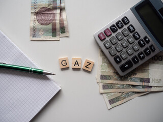 Gaz - napis z drewnianych kostek, podwyżki cen gazu, cena gazu, drogo, kalkulator, pieniądze, długopis, flatlay 