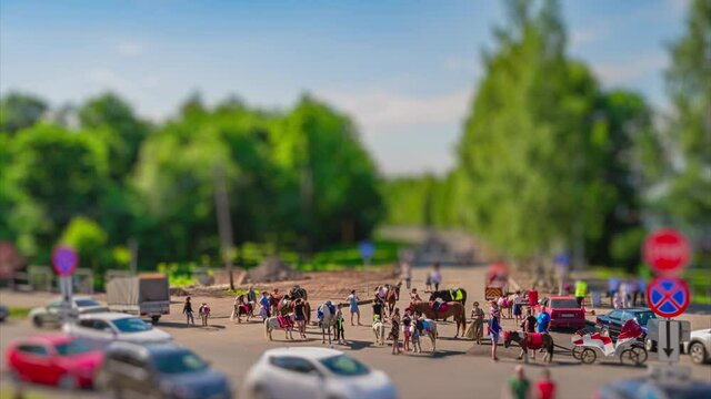 Time lapse. Tilt-shift of toy walking people, families with children, in recreation public park with many dressed up horses and fairy carriage for rent at summer sunny day. Holidays, vacation