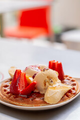 Vertical photo of delicious pancake with ice cream and fruits. Pancake dessert with strawberries and candy. Colombian food.
