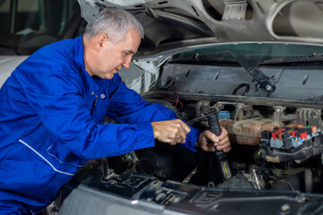 Fototapeta na wymiar Senior experienced mechanic repairing a car