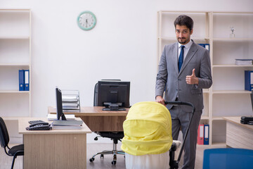 Young male employee looking after new born at workplace