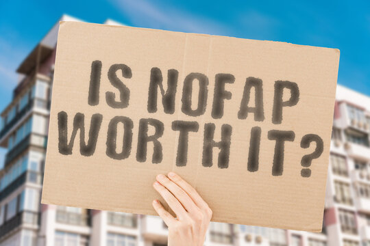 The question " Is NoFap Worth It? " on a banner in men's hand with blurred background. Love. Intimacy. Passionate. Manipulation. Erecting. Sexuality