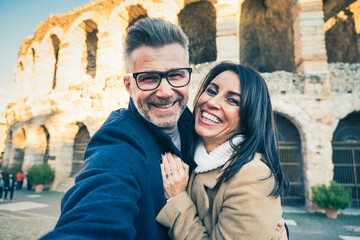 Happy couple of senior tourist having fun taking a selfie in front of famous monument of Italy - Vacation, tourism and travel concept
