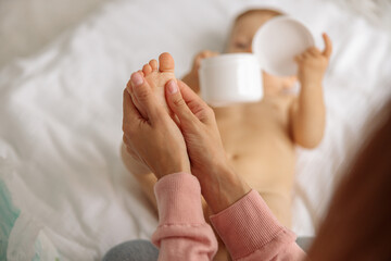 Mom massaging baby foot and using cream