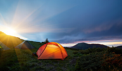 Illuminated orange camping tent under moon