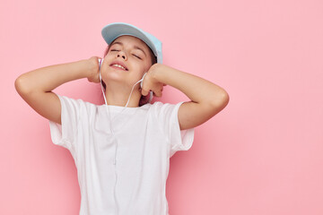cute girl headphones in a white t-shirt and a cap pink background