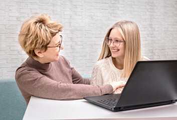 Mother and daughter laugh while sitting at the computer.