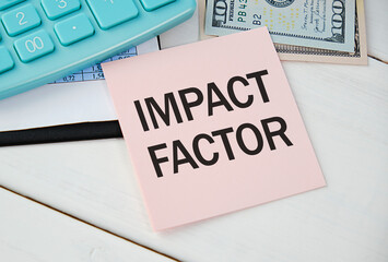 Card with text IMPACT FACTOR on white background, near office supplies and alarm clock.