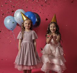 Two girls with balloons and confetti on a bright background,celebrating
