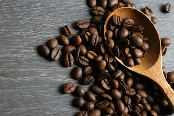 roasted coffee beans with wooden spoon on a wooden background close up