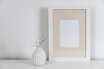 Blank canvas frame mockup. Artwork in interior design. View of modern scandinavian style interior with canvas for painting or poster on wall. Living room, commode with vases. Minimalism concept