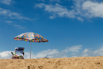 View from below, sun lounger with towels, beach parasol on the beach against the blue sky