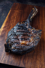 Modern style barbecue dry aged Chianina tomahawk steak served as close-up on a wooden design board