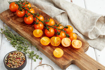 Fresh yellow cherry tomatoes on white wooden background