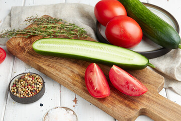 Fresh cucumbers and tomatoes on a wooden white background