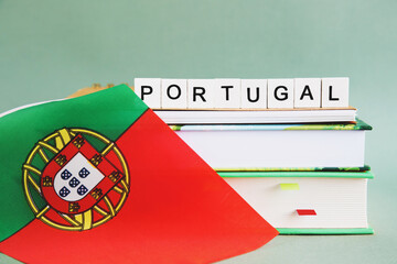 the inscription portugal on a stack of textbooks, books, exercise books and national flag of...