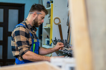 Bearded caucasian carpenter checking and measures drills