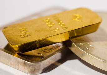 Gold ingot on top of a troy ounce silver bar