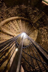 Old spiral staircase in deep and long undergrounds caves for making champagne sparkling wine from chardonnay and pinor noir grapes in Reims, Champagne, France