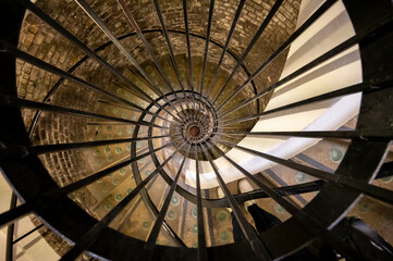 Old spiral staircase in deep and long undergrounds caves for making champagne sparkling wine from chardonnay and pinor noir grapes in Reims, Champagne, France
