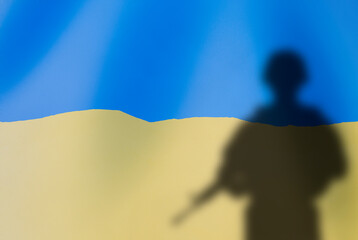 Conflict in Ukraine. The shadow of a soldier on the background of the Ukrainian flag.